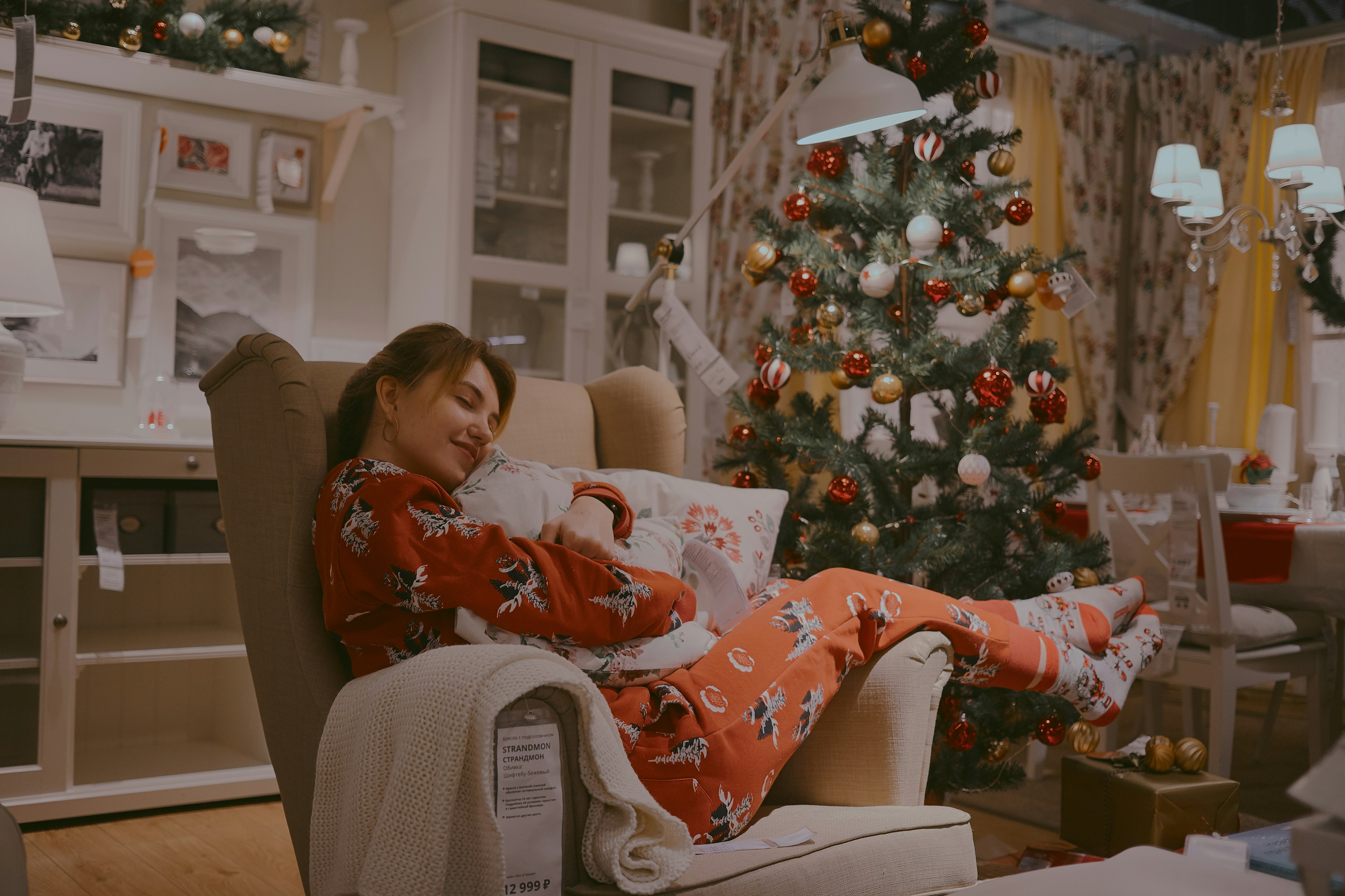 shallow focus photo of woman in orange long-sleeved shirt sitting on gray padded armchair